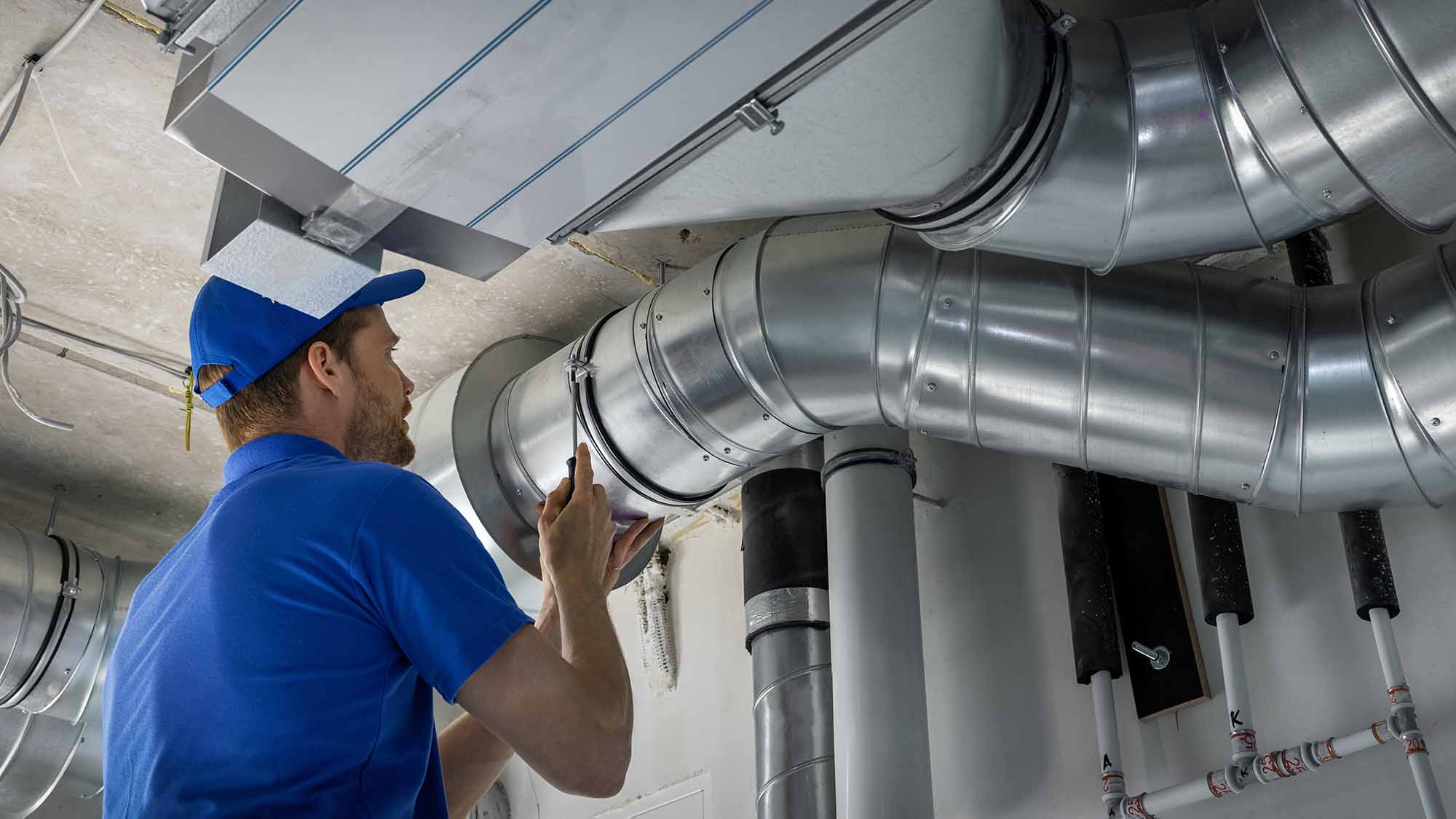 HVAC worker installing ducted pipe system