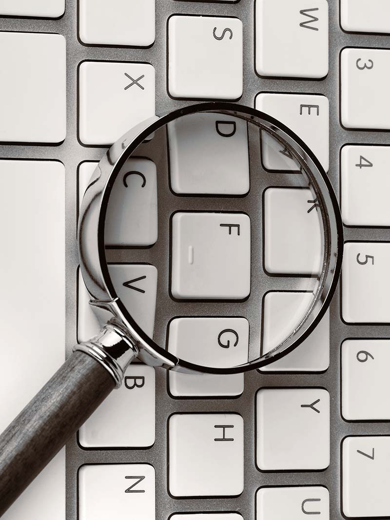 Magnifying glass on an white keyboard | Allegiant Digital