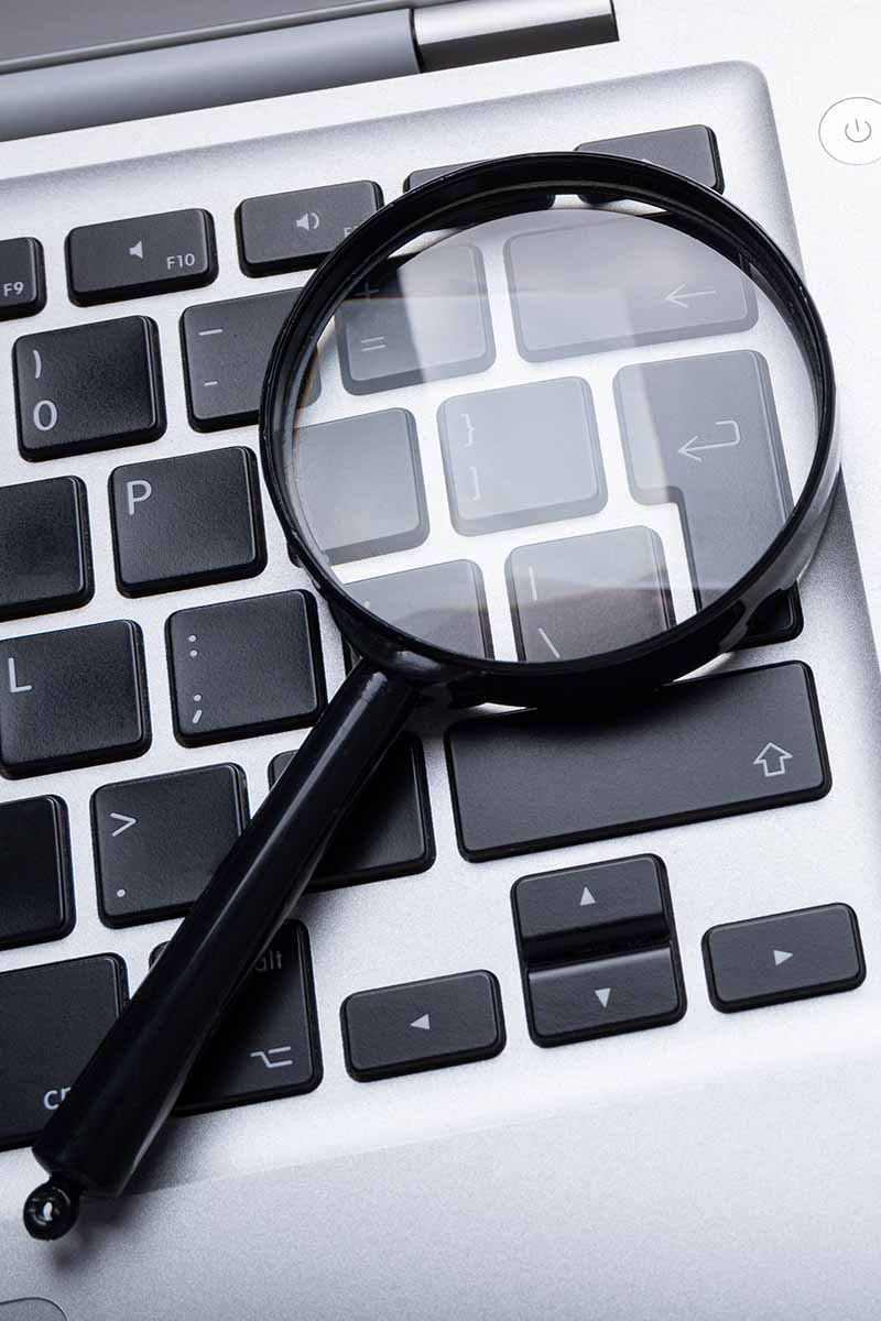 Magnifying glass laying on a laptop keyboard. | Allegiant Digital Marketing™
