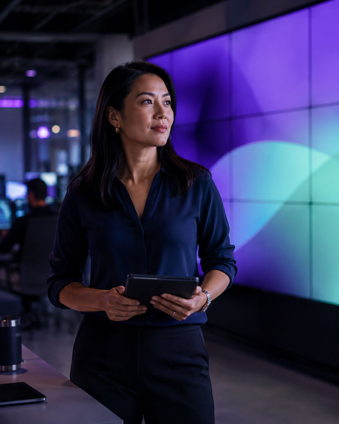 Operations leader in a modern operations space, abstract violet and mint wall display behind her